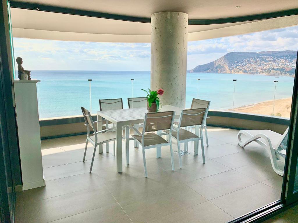 a dining room with a table and chairs and the ocean at Apartamento Infinium I - Exclusivo - Inmodream Calpe in Ifach