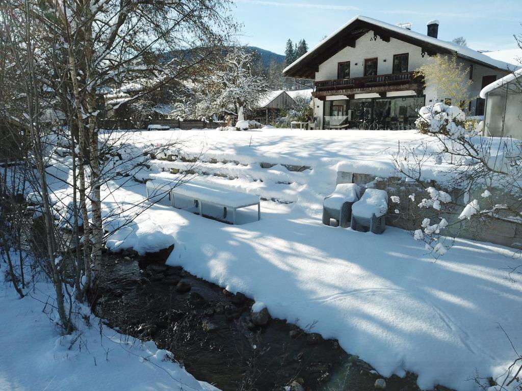 ein schneebedeckter Hof mit Bänken und einem Haus in der Unterkunft Pure Nature Munich - Alps in Fischbachau