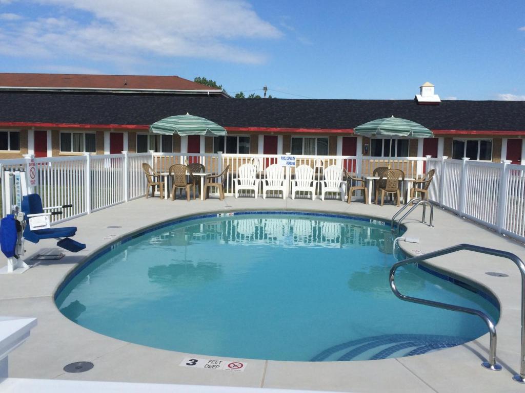 a swimming pool at a resort with tables and chairs at Caravan Motel in Niagara Falls