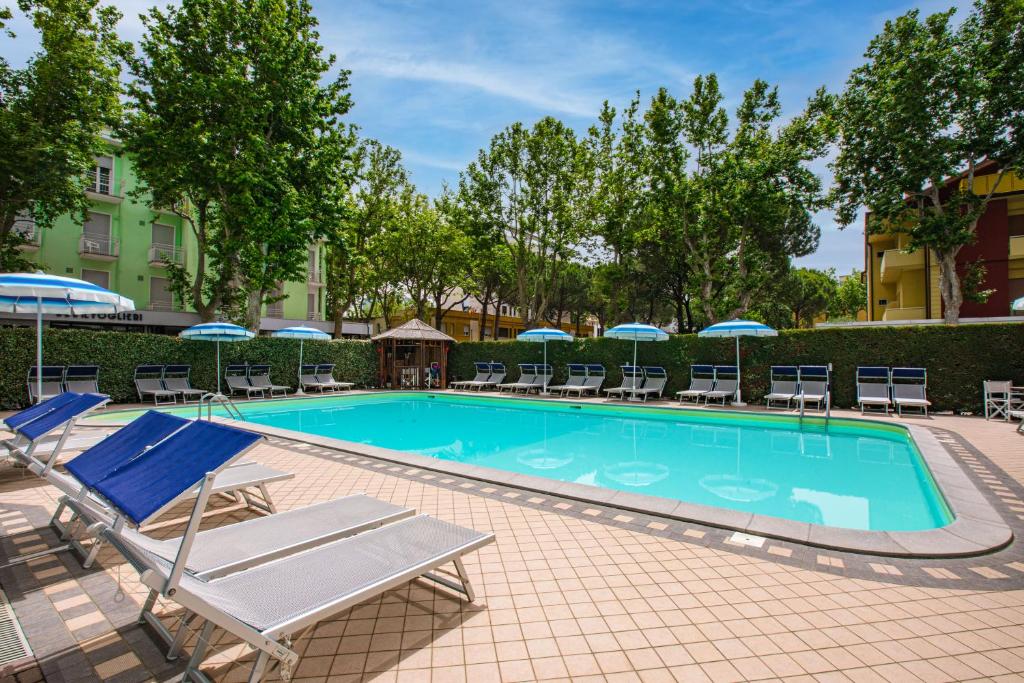 a swimming pool with lounge chairs and umbrellas at Hotel Stacchini in Cesenatico