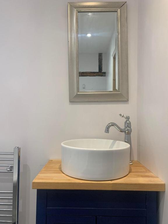 a bathroom with a white sink and a mirror at Lime Tree Cottage in Tillingham