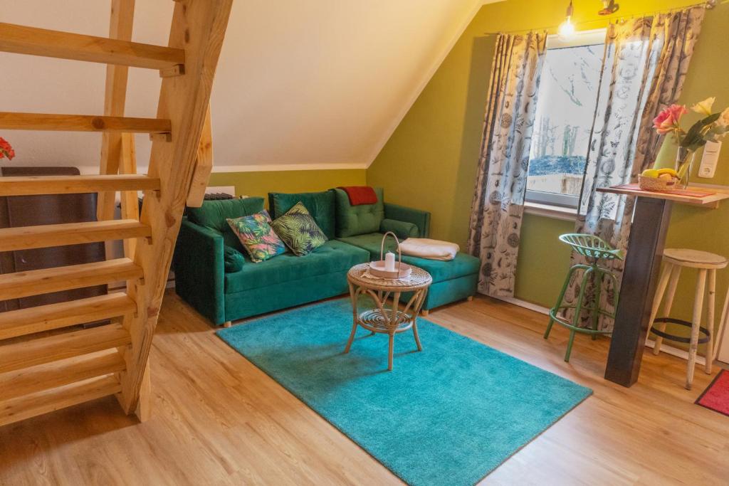 ein Wohnzimmer mit einem grünen Sofa und einem Tisch in der Unterkunft Maisonette am Glockenturm in Südbrookmerland