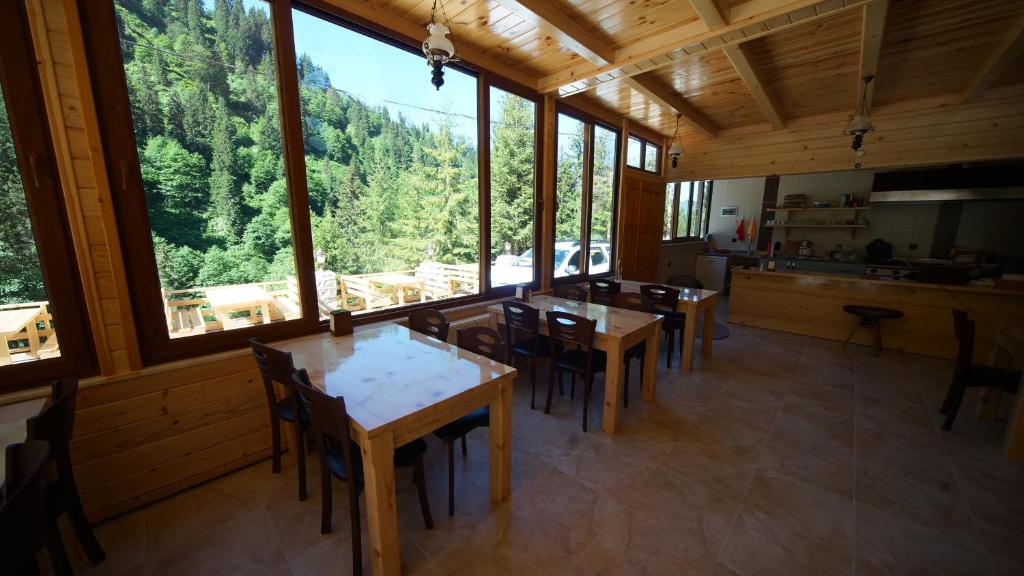 a kitchen and dining room with tables and windows at Ayder Cise Dag Evleri in Ayder Yaylasi