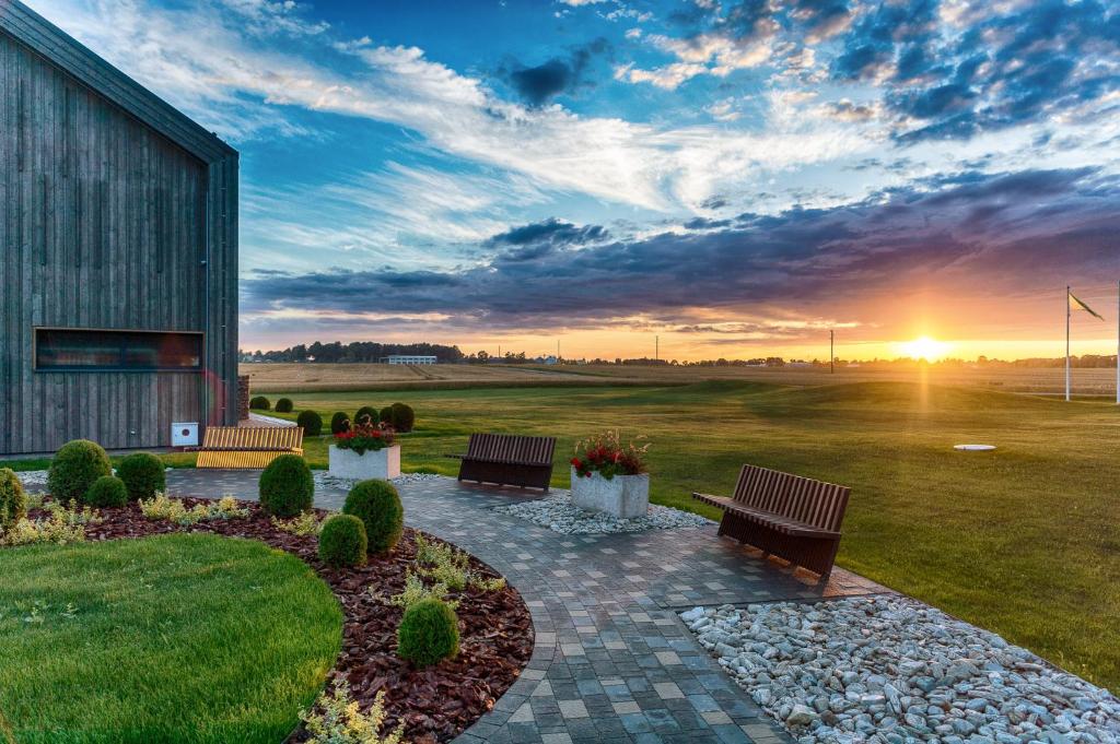 un patio con due panche e il tramonto sullo sfondo di Hotel Miķelis a Uzvara