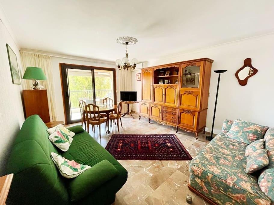 een woonkamer met een groene bank en een eetkamer bij Appartement T3 spacieux et lumineux de 70m2 in Bastia