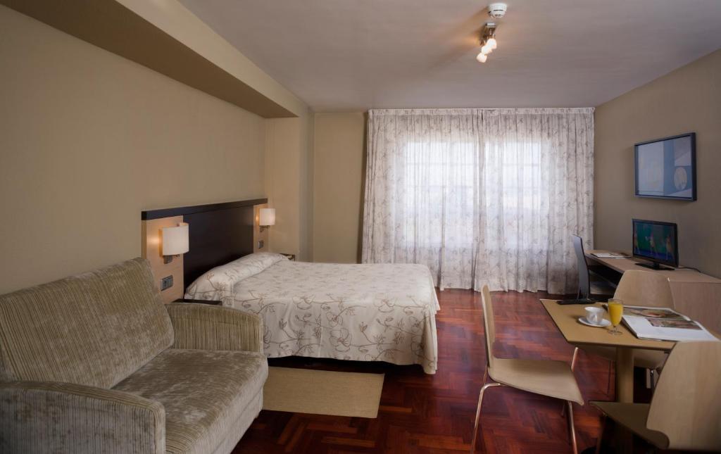 ア・コルーニャにあるApartamentos Portazgoのベッドとソファ付きのホテルルーム