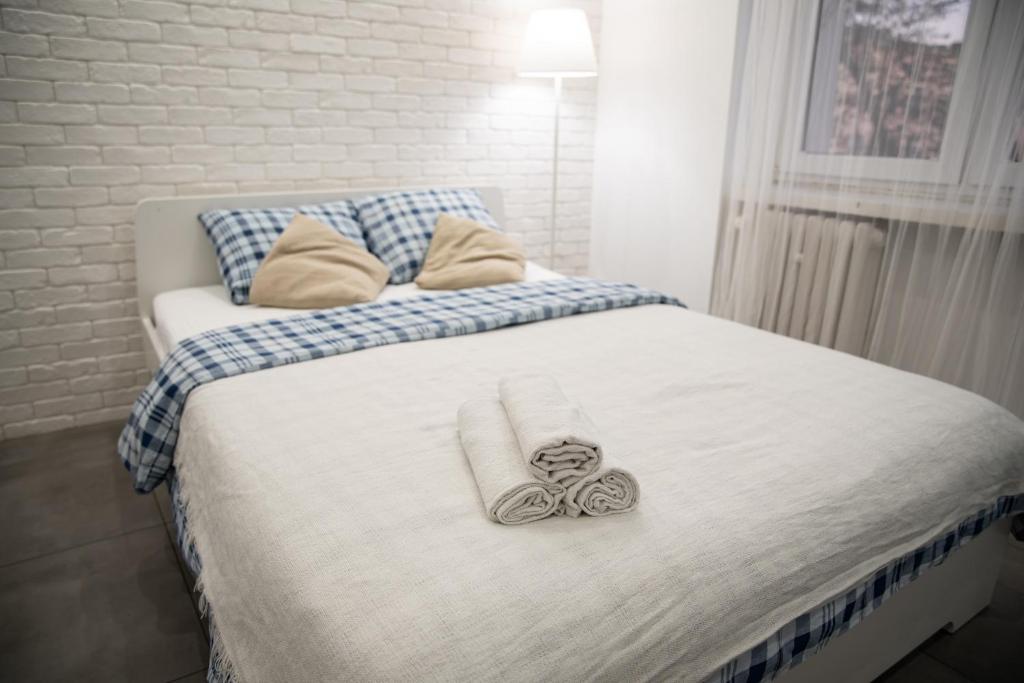 Una cama blanca con un par de toallas. en Apartament Estakada 2, en Częstochowa