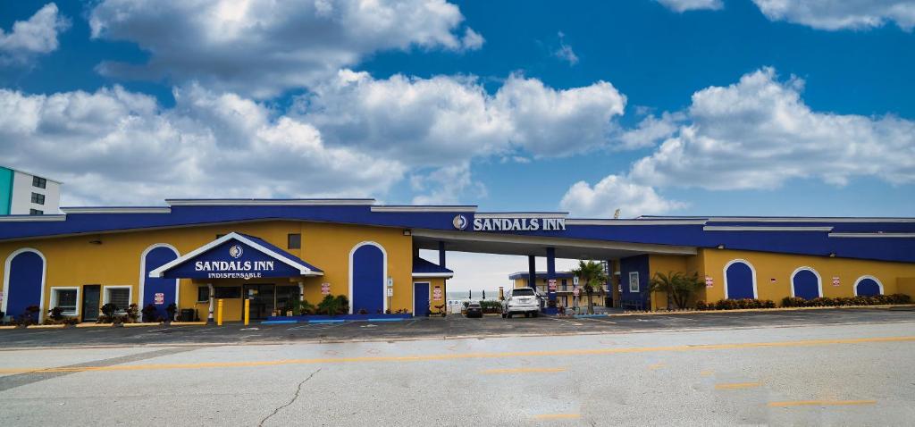 a yellow and blue building with a parking lot at Sandals Inn in Daytona Beach
