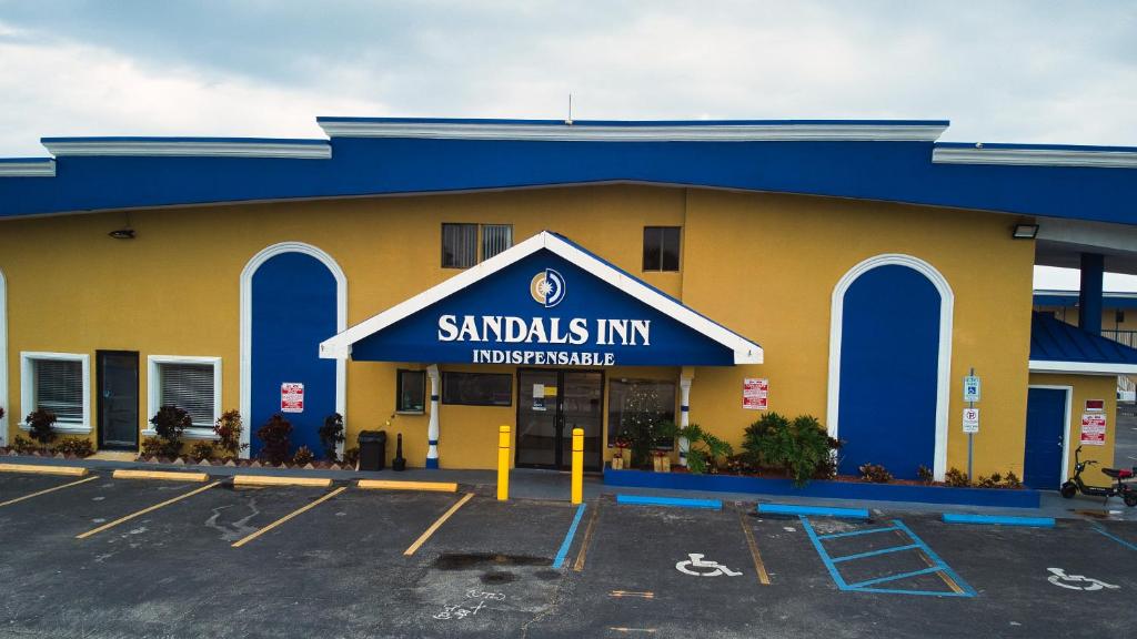 um grande edifício com uma placa que lê sanduíches pousada em Sandals Inn em Daytona Beach
