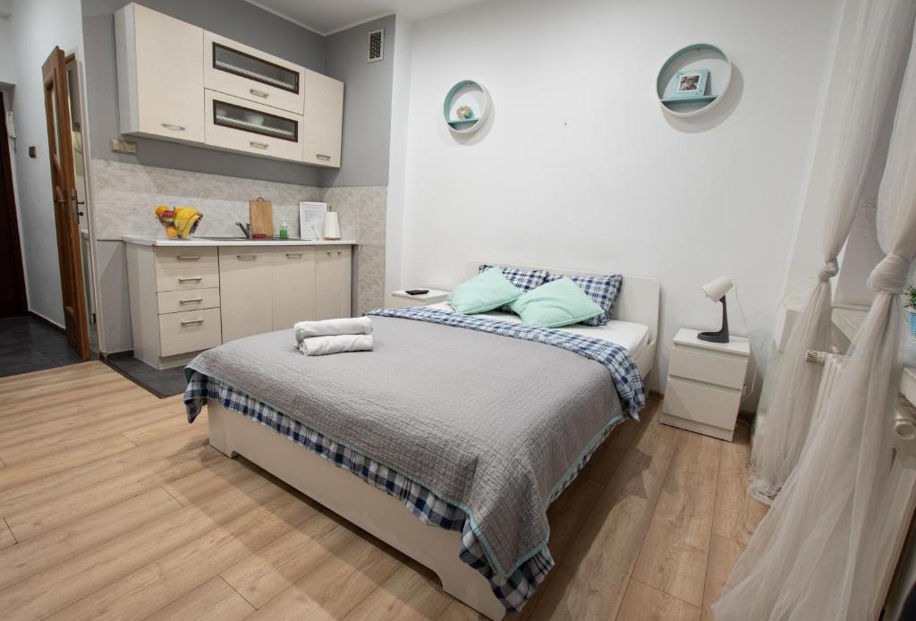 a white bedroom with a bed and a kitchen at Apartament Estakada in Częstochowa