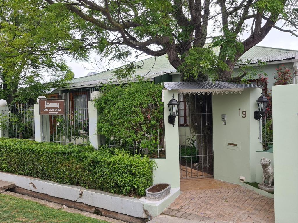 a white house with a gate and a tree at Knysna Self Catering Accommodation in Knysna
