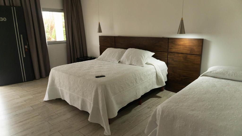 a bedroom with a white bed and a wooden headboard at Hotel Oaky in Posadas