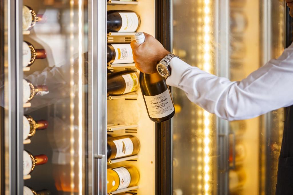 a man is holding a bottle of wine in a refrigerator at InterContinental Cascais-Estoril by IHG in Estoril
