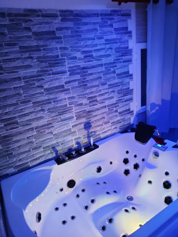 bañera en una habitación con pared de ladrillo en DÉPENDANCE EN CHAMBRE D'HÔTE AVEC JACUZZI PRIVATIF DANS LA CHAMBRE v, en Amblainville