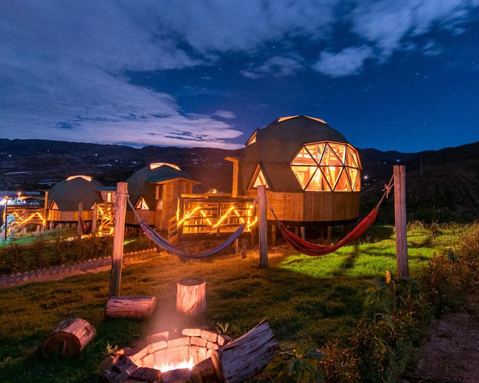 a large building with a hammock next to a fire pit at Los Nopales Glamping in Sáchica