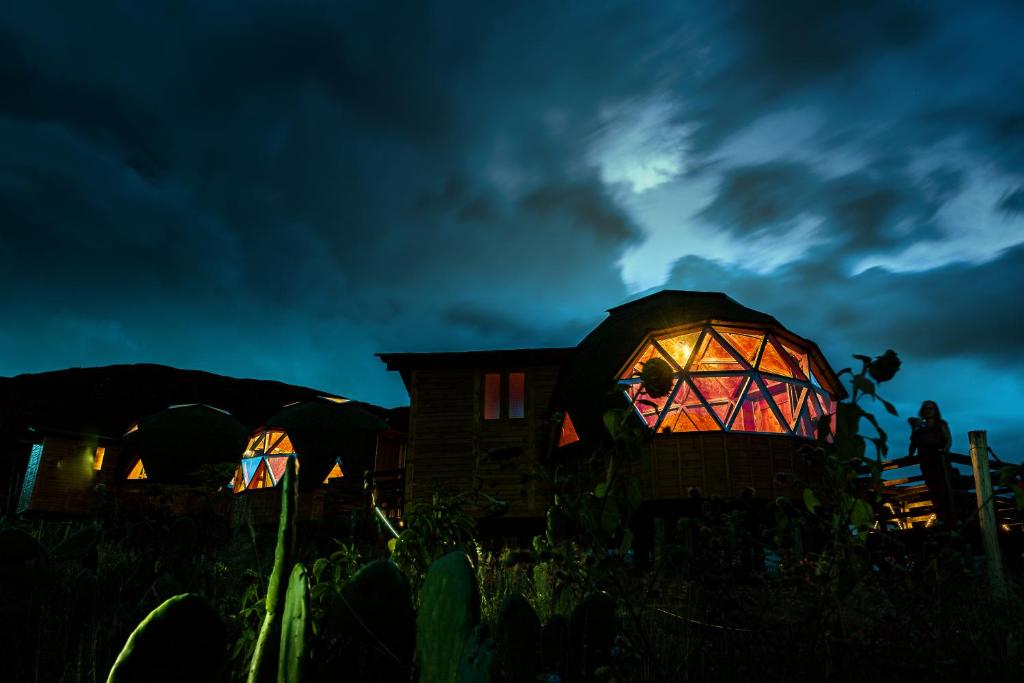 a group of igloo homes lit up at night at Los Nopales Glamping in Sáchica