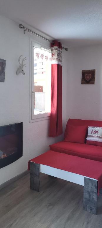 un soggiorno con divano rosso e finestra di Appartement sur le Parc des Ecrins a Puy-Saint-Vincent