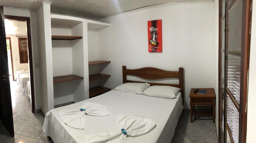 a small bedroom with a white bed and a table at Hotel Pousada Nosso Cantinho in Ubatuba