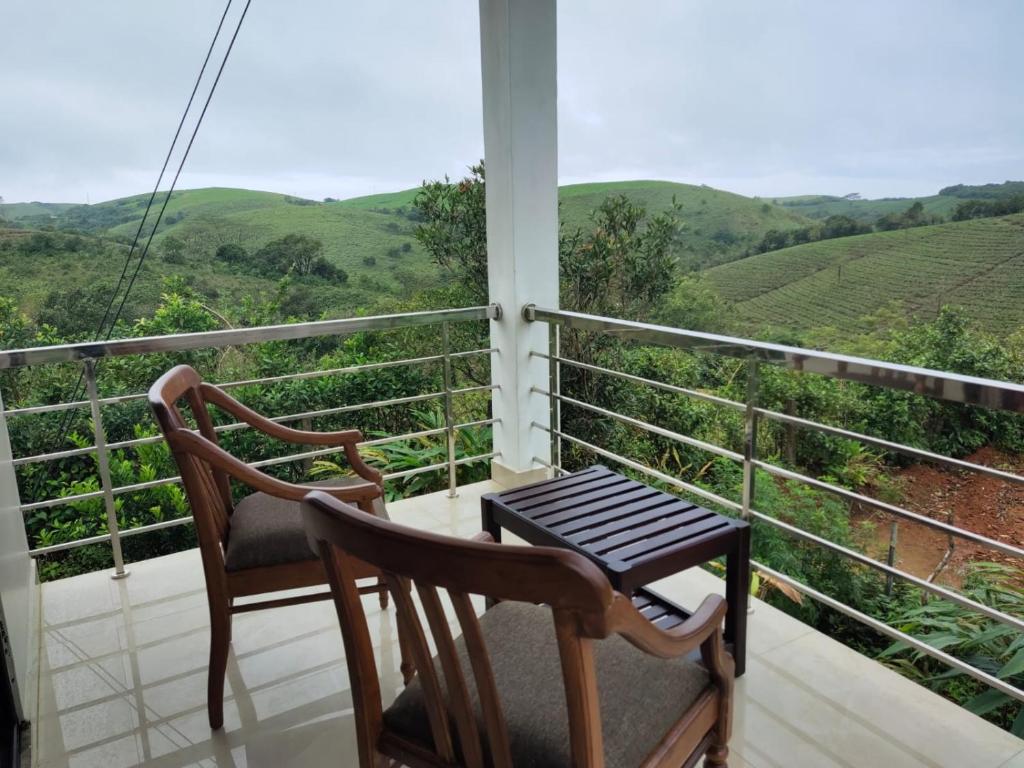 a balcony with two chairs and a table and a view at CeeCee Grand Resort in Vagamon