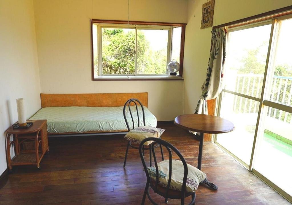 a bedroom with a bed and a table and chairs at Ikokujyoucho - Vacation STAY 97595v in Nishinoomote