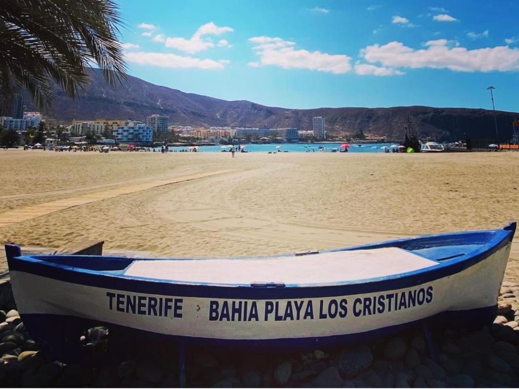 um barco sentado numa praia arenosa com o oceano em Almar Apartamento en Los Cristianos con AC em Los Cristianos