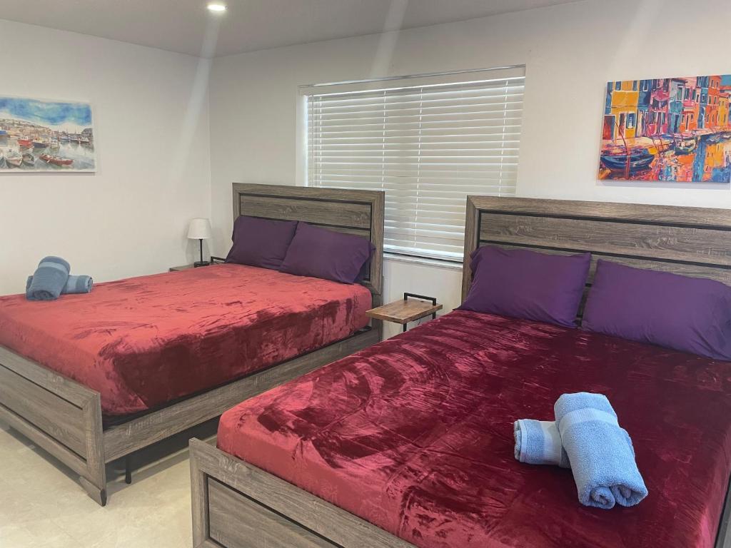 een slaapkamer met 2 bedden met rode lakens en paarse kussens bij New Boutique 1 Bdrm Close To Beach & Casino #211 in Hollywood