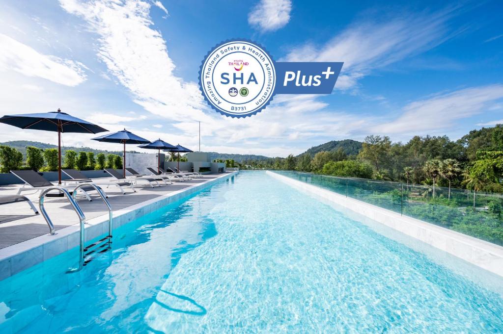 una piscina con sillas y sombrillas en un hotel en Kokotel Phuket Nai Yang Beach - SHA Extra Plus, en Nai Yang Beach