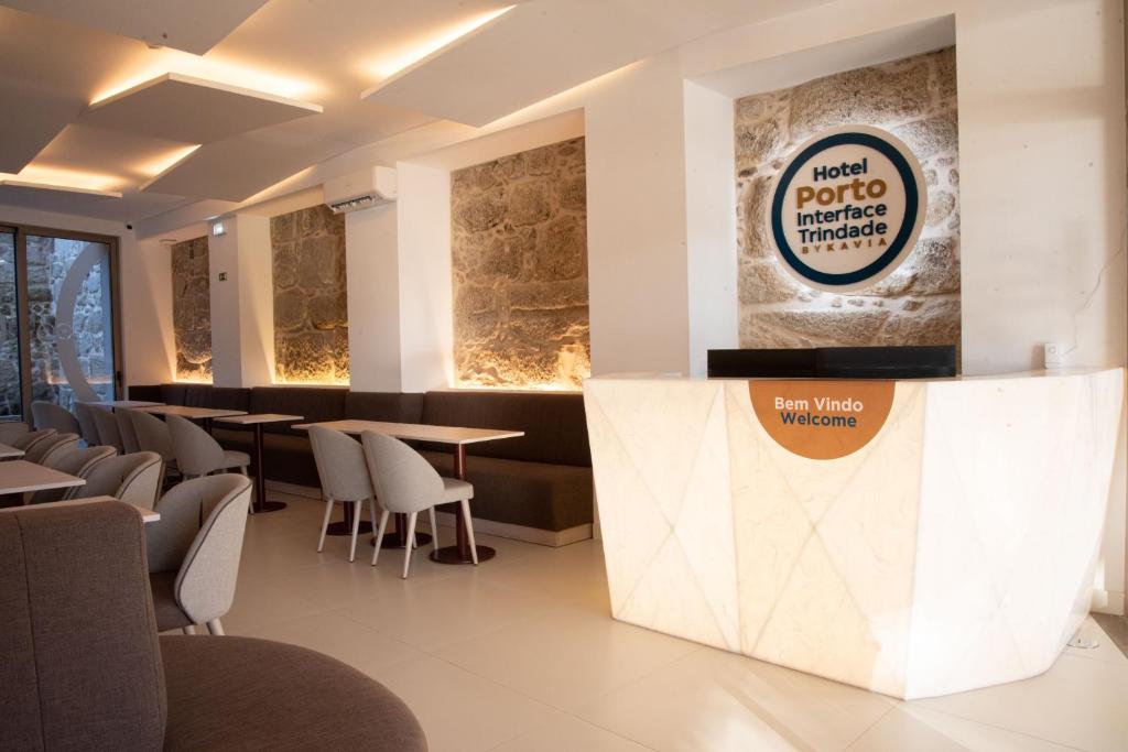 a restaurant with tables and chairs and a sign on the wall at Hotel Porto Interface Trindade By Kavia in Porto