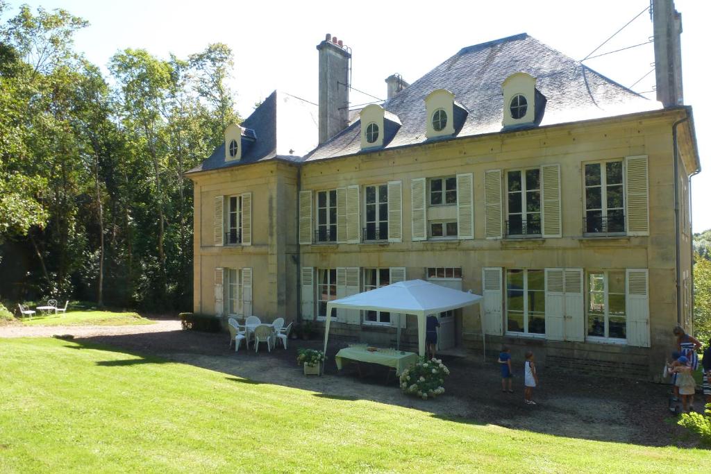 une grande maison avec des personnes debout devant elle dans l'établissement Maison de vacances _ Le Bas Manoir, à Bretteville-sur-Odon