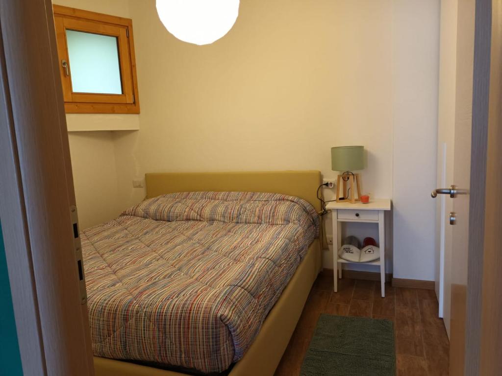 a small bedroom with a bed and a small table at Ampio e grazioso trilocale con vista panoramica in Chiesa in Valmalenco