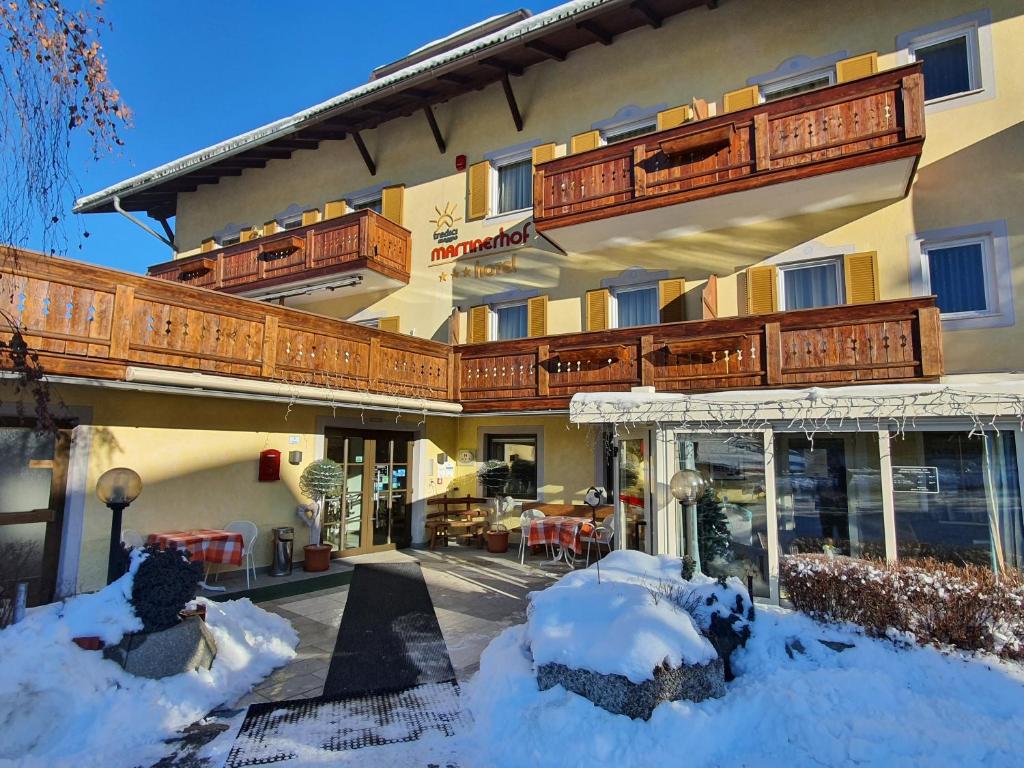 un grand bâtiment avec de la neige au sol dans l'établissement Hotel Martinerhof, à San Lorenzo di Sebato