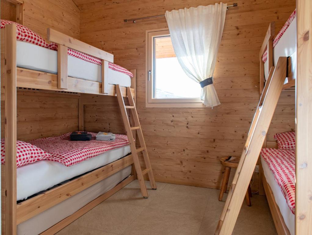 two bunk beds in a wooden room with a window at Chalet Diognysos B&B, Boutique Hotel & Wellness in Crans-Montana