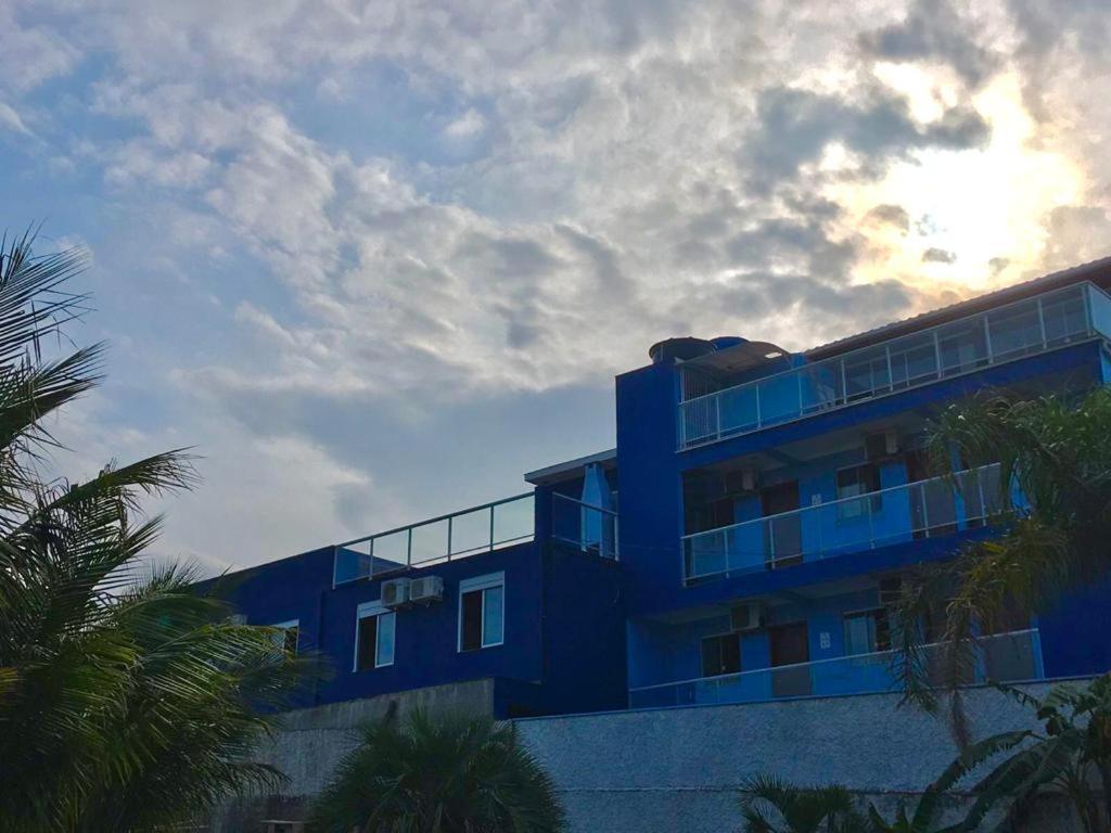 un edificio azul con palmeras delante en Residencial Gralha Azul en Florianópolis