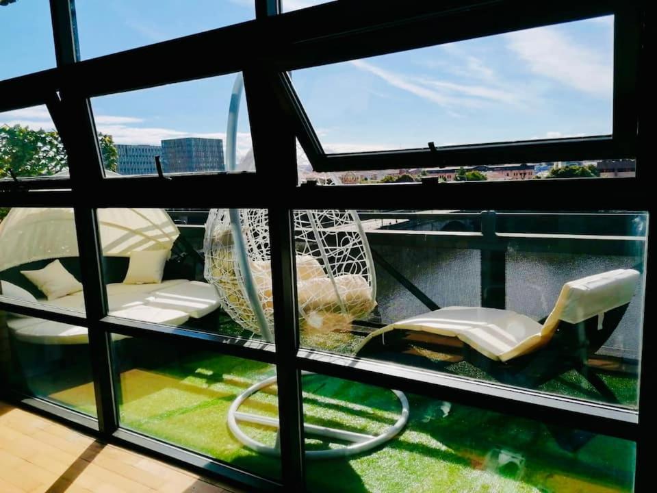 a view from the window of a balcony with chairs at Glasgow City Centre G1 PENTHOUSE with RiverViews - Duplex (4 Bedrooms, 3 Bathrooms, Kitchen, 1 Living room, 1 Dining room, 2 Terraces, Triple Garage 3 Parking spaces 'e-charging', Top Floor, 2050 sq ft, Merchant City) in Glasgow