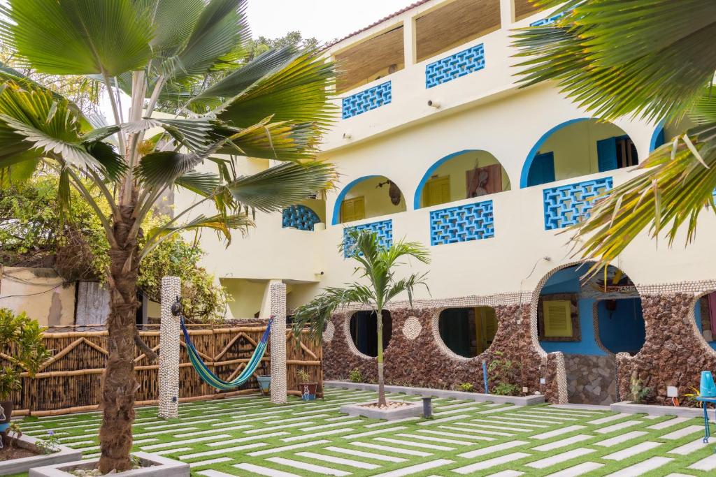 ein Gebäude mit Palmen davor in der Unterkunft Hotel Mimosa Airport in Toubab Dialao
