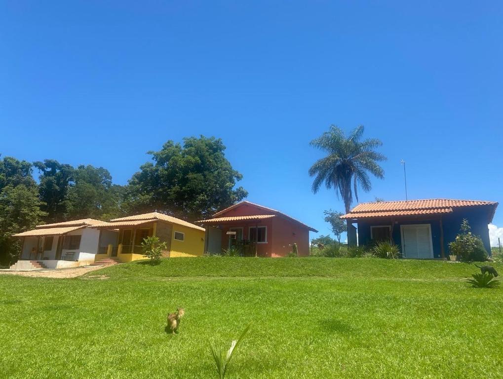 un patio con dos casas y un pájaro en el césped en Chale Cantinho de Minas en São João Batista do Glória