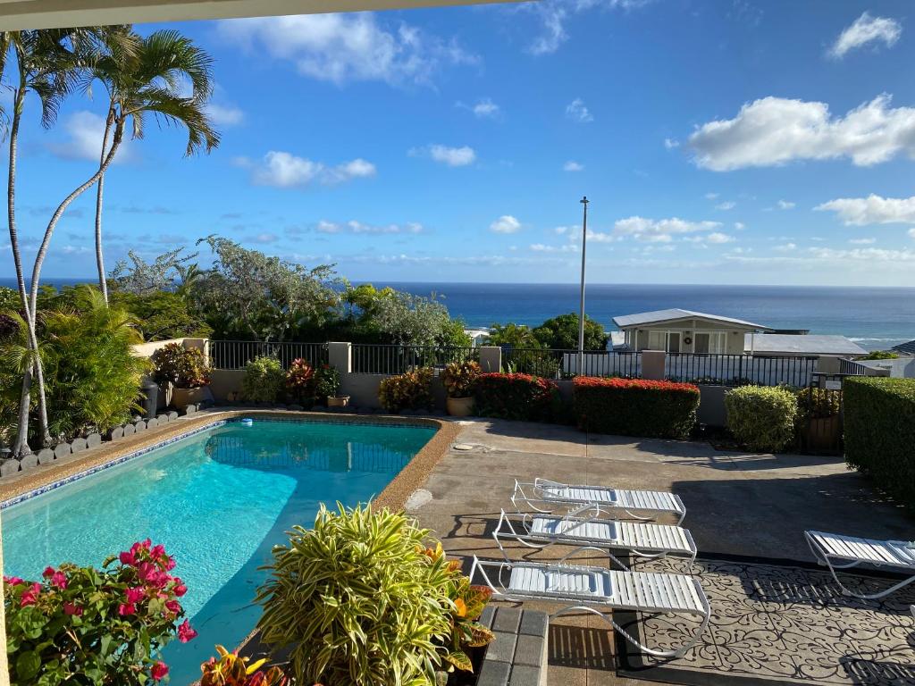 una piscina con sillas y el océano en el fondo en Paradise at Ehupua en Honolulu