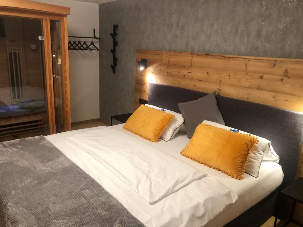 ein Schlafzimmer mit einem Bett mit zwei orangefarbenen Kissen in der Unterkunft Apart EMMA in Finkenberg