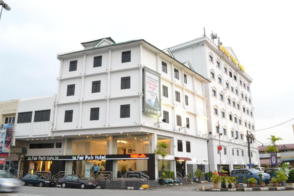 un edificio blanco con coches estacionados frente a él en Fair Park Hotel en Ipoh