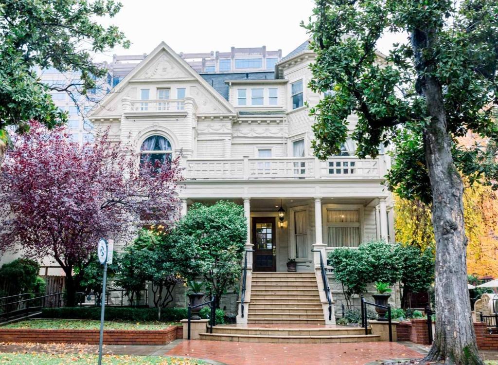 a white house with stairs and trees in front of it at The Sterling Hotel in Sacramento