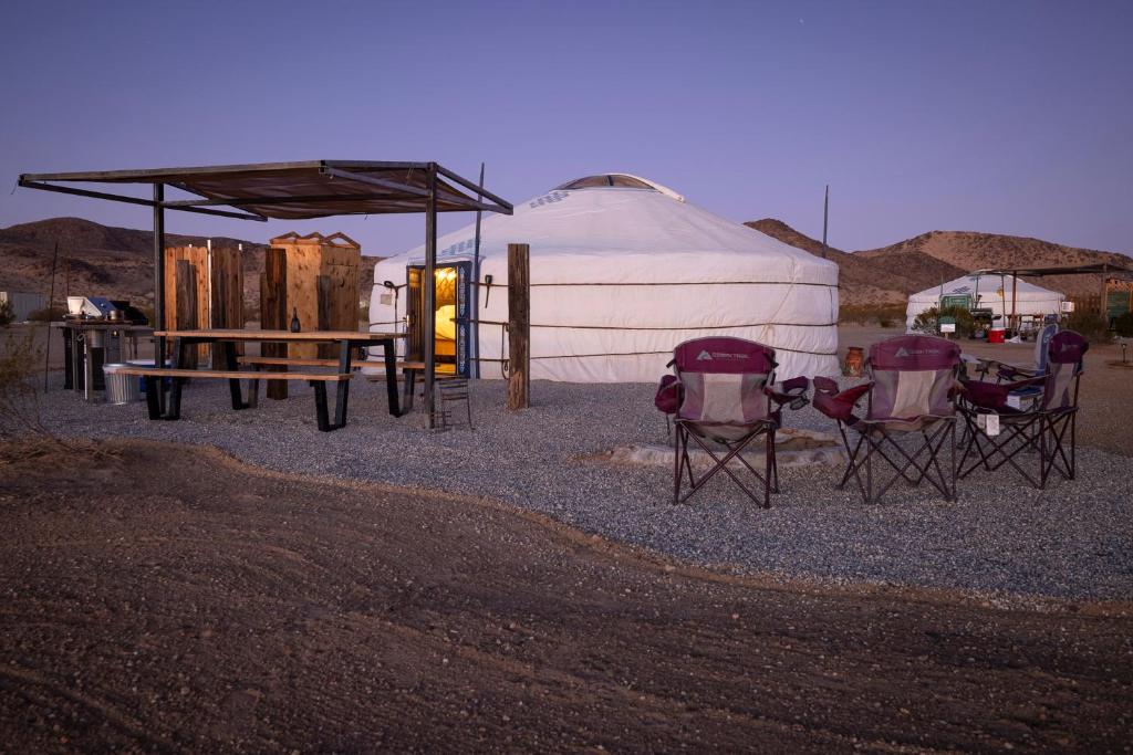 Family Style Star gazing Yurt في تونتي ناين بالمز: مجموعة كراسي وخيمة في الصحراء