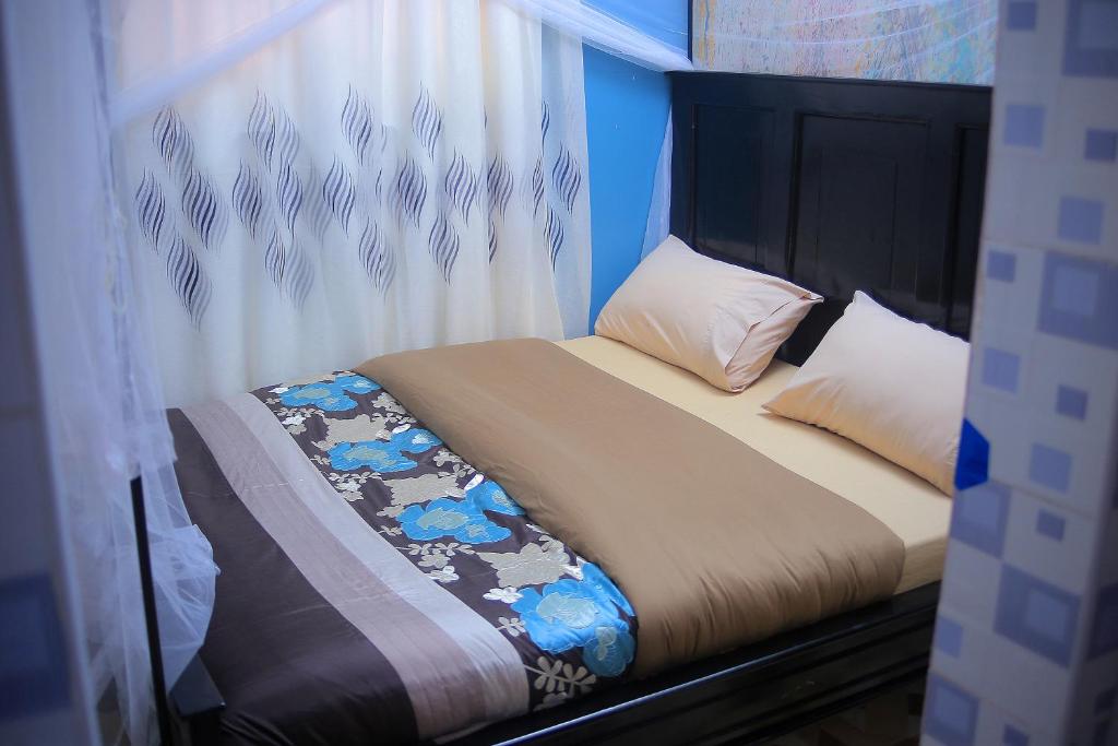 - un lit avec une tête de lit et des oreillers dans l'établissement Awooooo Accommodation Kampala, à Kampala