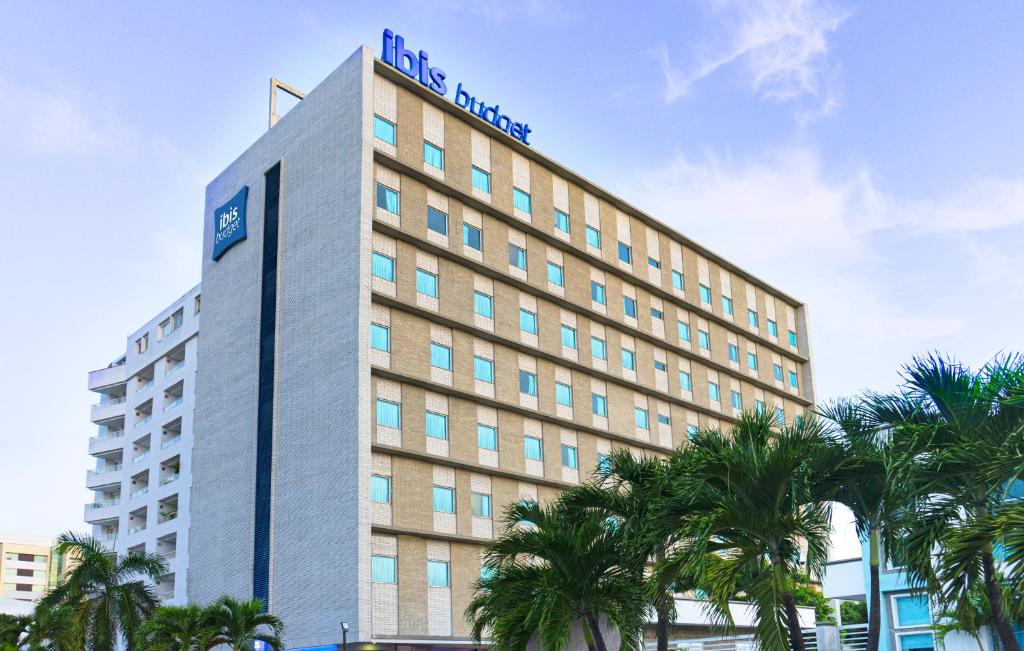 un edificio de hotel con palmeras delante en ibis budget Barranquilla, en Barranquilla