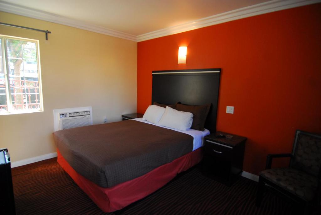 Habitación de hotel con cama y pared de color naranja en Studio City Inn - Near Universal Studios Hollywood en Los Ángeles
