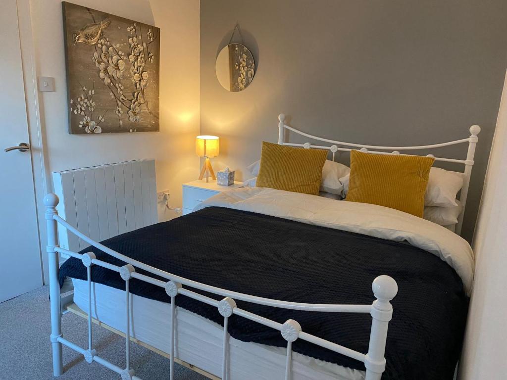 a bedroom with a white bed with yellow pillows at Cosy 2 Bed Flat 1 in Bridgend in Bridgend