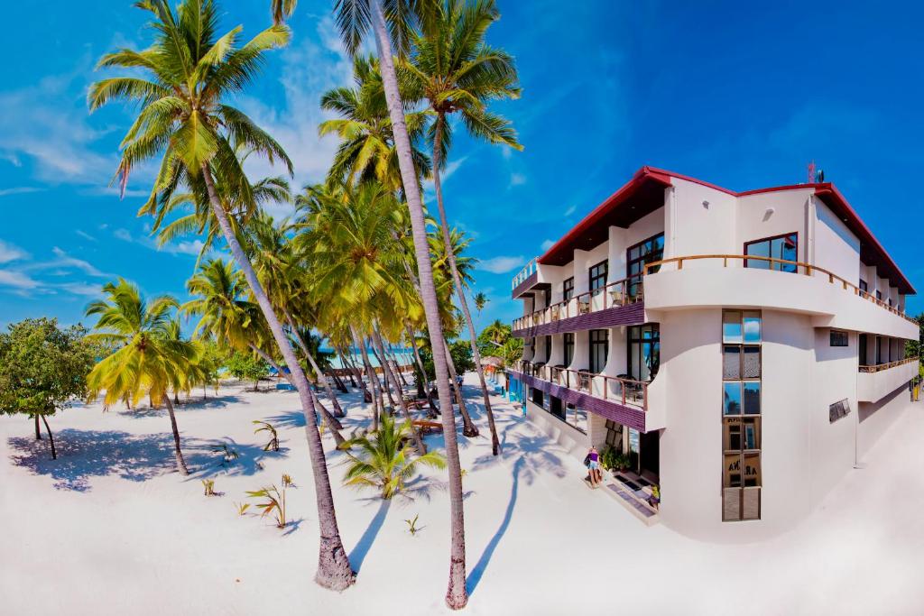 a hotel on the beach with palm trees at Kaani Beach Hotel in Maafushi