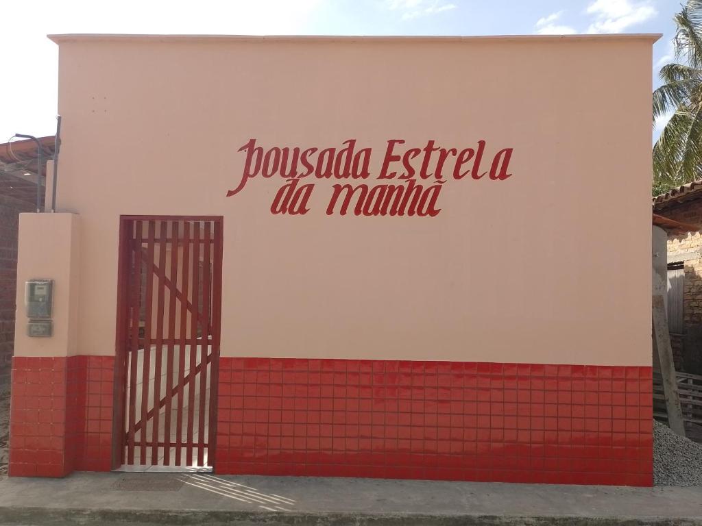 a building with a red and white wall with a gate at pousada estrela da manhã in Santo Amaro