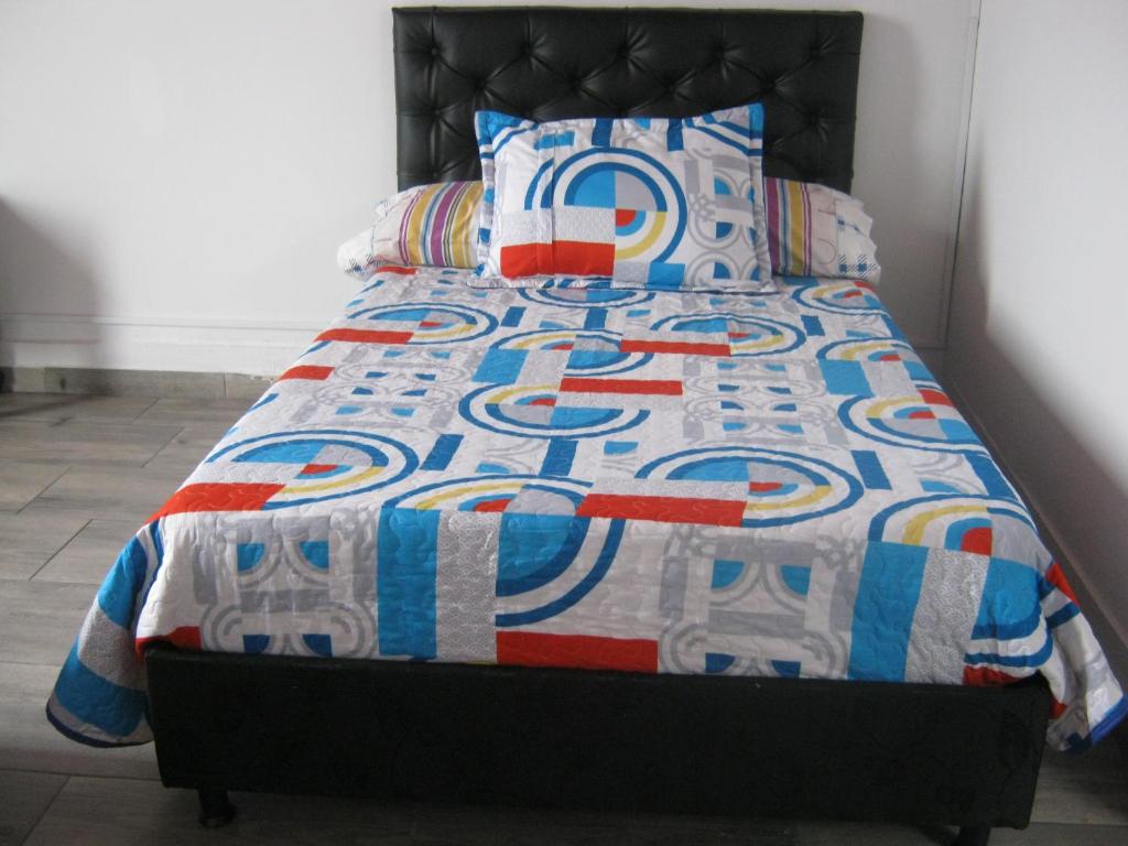 un letto con trapunta e cuscini sopra di ANGIE`s HOUSE a Manizales