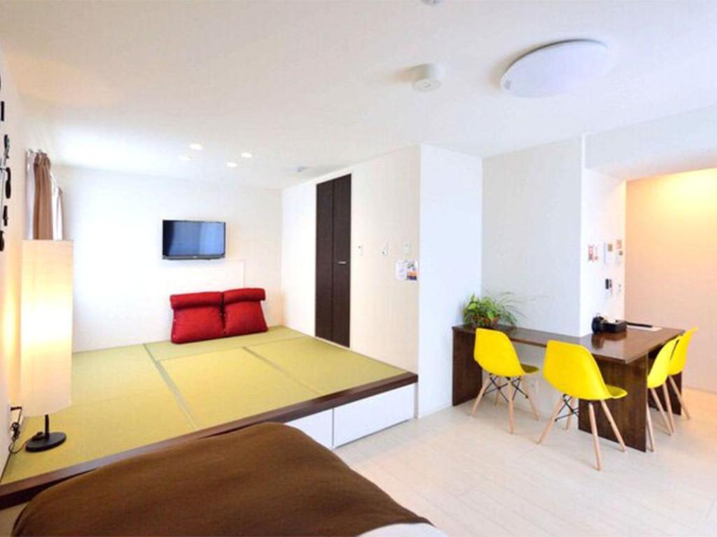 Zimmer mit einem Bett, einem Tisch und gelben Stühlen in der Unterkunft Guest House Gifuhashima COCONE / Vacation STAY 33938 in Hashima