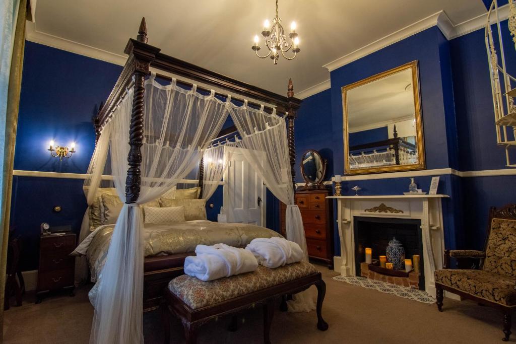 a bedroom with a canopy bed and a fireplace at Heytesbury House in Cobden